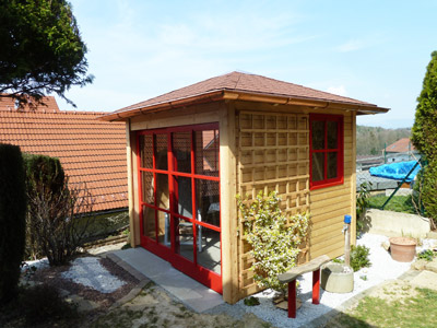 Gartenhaus mit roten Fenstern und Tueren
